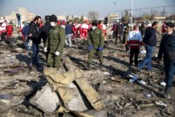 FILE - Security officers and Red Crescent workers are seen at the site where the Ukraine International Airlines plane crashed after take-off from Iran's Imam Khomeini airport, on the outskirts of Tehran, Iran, Jan. 8, 2020.