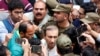 FILE - Police officers and journalists surround Mir Shakil-ur-Rahman, the owner and editor-in-chief of Geo television news channel and the Jang group of newspapers, as he leaves after court proceedings in Lahore, Pakistan, March 13, 2020.