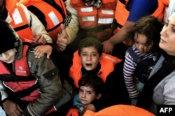 FILE - Syrian Kurdish refugees are rescued by Greek fishermen as the boat they were on sinks off the Greek island of Lesbos after crossing the Aegean Sea from Turkey, Oct. 30, 2015.