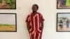 Nigerian photojournalist Damilola Onafuwa poses with some photos he took from conflict areas for the Center for Civilians in Conflict, in Abuja, September 21, 2021. (Timothy Obiezu/VOA) 