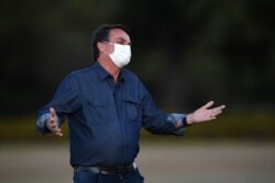 Brazilian President Jair Bolsonaro gestures while attending the flag unveiling ceremony at the Alvorada Palace in Brasilia, on July 15, 2020. - Brazil President Jair Bolsonaro tested positive for coronavirus again, CNN Brazil said on Wednesday,…