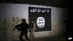 In this March 1, 2017 file photo, an Iraqi soldier inspects a recently-discovered train tunnel, adorned with an Islamic State group flag. 