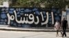 A Palestinian man and his daughter walk past a graffiti reading in Arabic ''Division'' in Gaza City, on Sept. 17, 2017, after Hamas announced it had agreed to steps toward resolving a decade-long split with the Fatah movement.