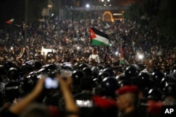 Jordanian protesters shout slogans and raise a national flag during a demonstration outside the Prime Minister's office in the capital Amman, June 4, 2018.