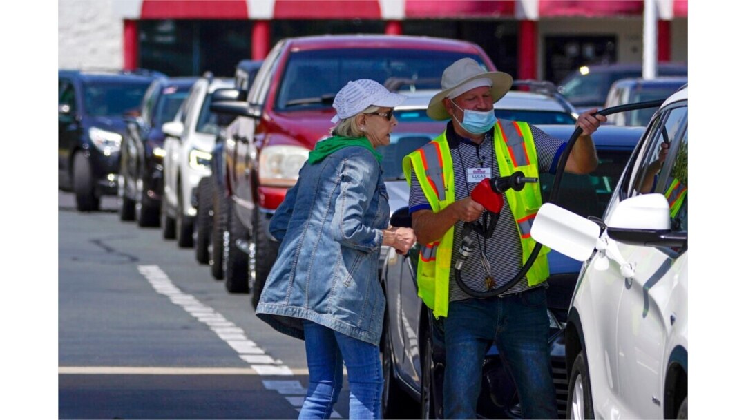 FILE - A customer helps pump gas at Costco, as others wait in line, in Charlotte, N.C., May 11, 2021.