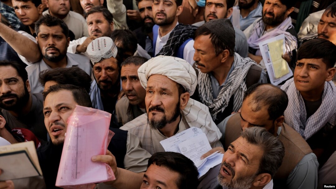 Afghans gather outside the passport office after Taliban officials announced they will start issuing passports to its citizens again, following months of delays that hampered attempts by those trying to flee the country after the Taliban seized control, i