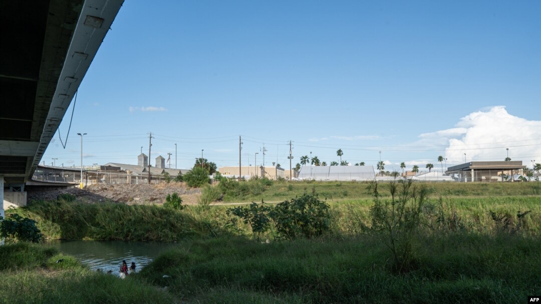 Migrantes lavan ropa y se bañan en las orillas mexicanas del Río Grande. Por encima está el Puente Internacional en Matamoros, estado de Tamaulipas, México, el 5 de noviembre de 2019.