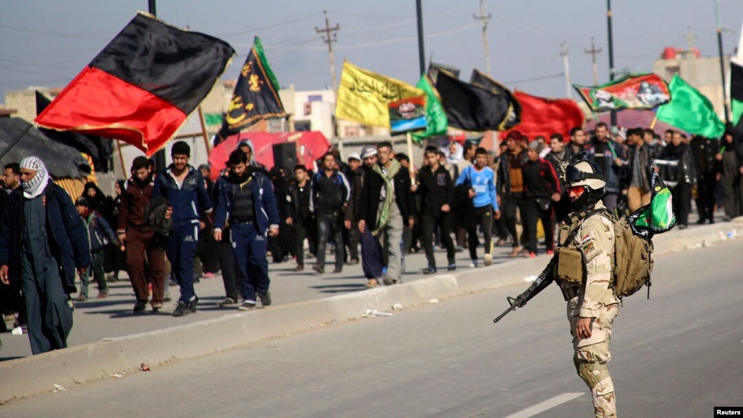 An Iraqi soldier stands guard as Shi'ite pilgrims walk to the holy city of Kerbala, ahead of the religious ceremony of Arbain, in Baghdad, Dec. 21, 2013. 