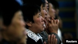 FILE - A woman prays with other villagers during a Mass in the morning at the Liuhe Catholic Church in Liuhe village on the outskirts of Qingxu county, Shanxi province, China, Sept. 11, 2011.