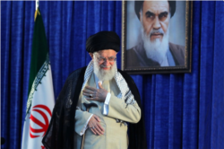 FILE - Iranian Supreme Leader Ayatollah Ali Khamenei gestures to a crowd at a June 4, 2019 ceremony in Tehran marking the 30th anniversary of the death of his predecessor, Ayatollah Ruhollah Khomeini, whose portrait appears behind him.