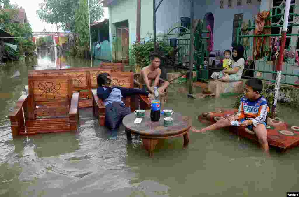 Residents sit as they clean up their property following floods at a residents area in Makassar, South Sulawesi, Indonesia, in this photo taken by Antara Foto.