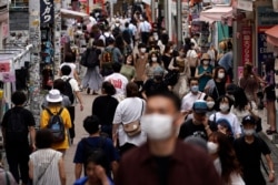 People wearing face masks to help curb the spread of the coronavirus walk through a shopping area in Tokyo, July 3, 2020.