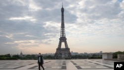 FILE - In this April 24, 2020, photo, a man wears a mask to protect against the spread of the coronavirus as he walks along the Trocadero square close to the Eiffel Tower in Paris.