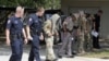 Law enforcement officials conduct a grid search of an area where police say a gunman was being served an eviction notice when he opened fire from inside a home near Texas A&M and killed a law enforcement officer Monday, Aug. 13, 2012, in College Station,