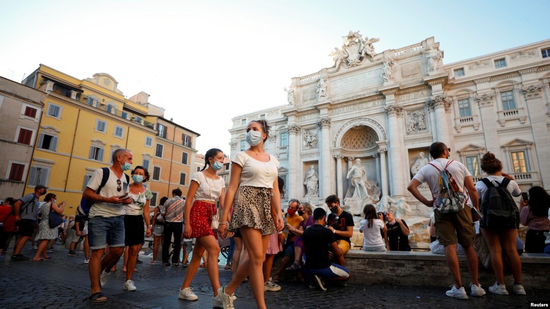 Transeúntes y turistas con máscaras junto a la Fuente de Trevi, una de las principales atracciones de Roma.