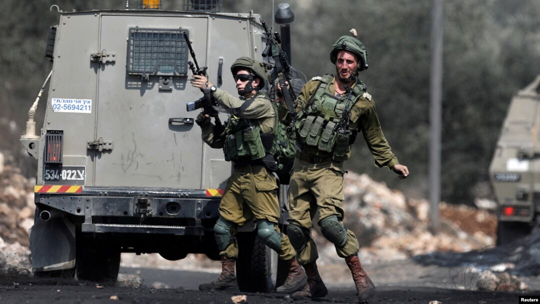 A stone is thrown at an Israeli soldier during clashes with Palestinians following a protest against the near-by Jewish settlement of Qadomem, in the West Bank village of Kofr Qadom near Nablus, Aug. 25, 2017.