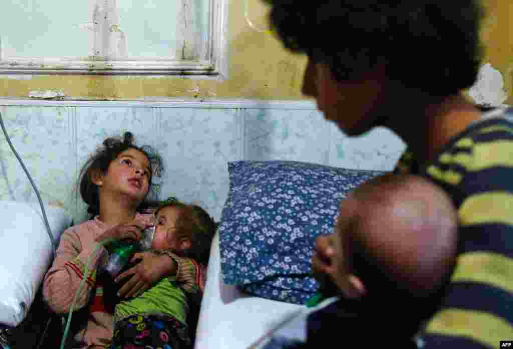 A Syrian girl holds an oxygen mask over the face of an infant at a make-shift hospital following a reported gas attack on the rebel-held besieged town of Douma in the eastern Ghouta region on the outskirts of the capital Damascus, Jan. 22, 2018.