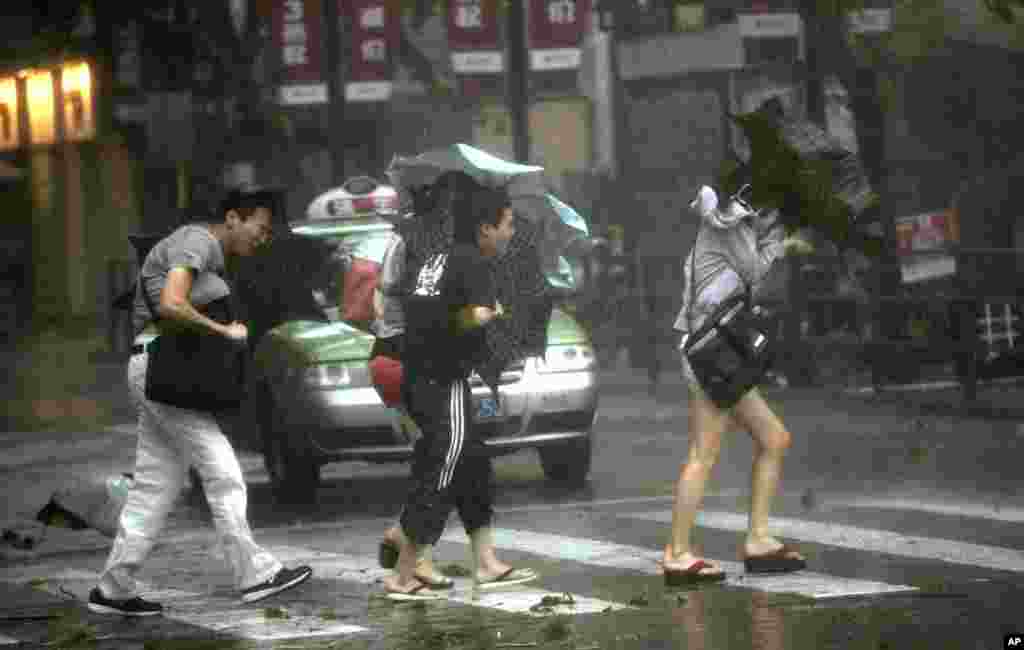 People walk in a rainstorm brought on by Typhoon Haikui in Shanghai, China, August 8, 2012.