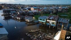 Los espectadores se sientan en botes viendo una película proyectada en una pantalla instalada sobre una estructura de madera durante el Festival de Cine Flotante Muyuna, que celebra los bosques tropicales, en el barrio Belén de Iquitos, Perú, el 25 de mayo de 2024.