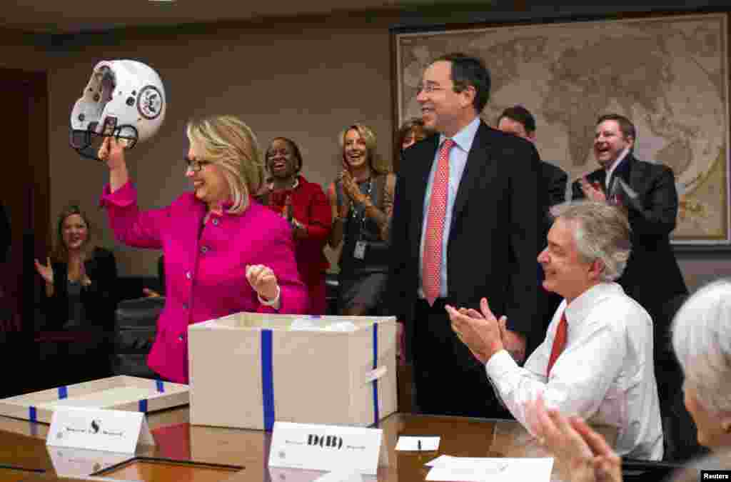 Clinton holds up a football helmet with the State Department logo on it, presented by Deputy Secretary Thomas Nide, who joked that "Washington is a contact sport," January 7, 2013.