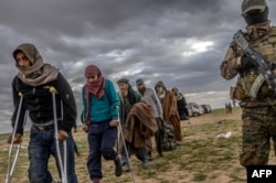 FILE - Men suspected of being Islamic State fighters wait to be searched by members of the Kurdish-led Syrian Democratic Forces (SDF) after leaving the IS group's last holdout of Baghuz, in Syria's northern Deir Ezzor province, Feb. 27, 2019.