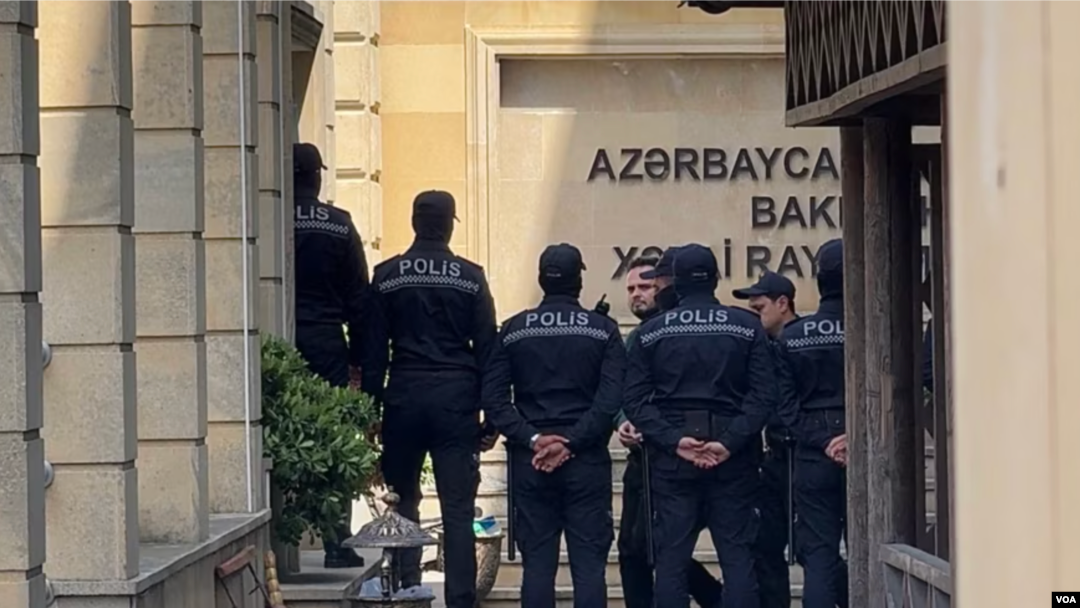 Farid Mehralizada, an economist and journalist for Radio Free Europe/Radio Liberty’s Azerbaijani Service, is guarded by police in this undated photo.