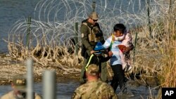ARCHIVO - Migrantes son detenidos por funcionarios en la frontera entre Texas y México, el 3 de enero de 2024, en Eagle Pass, Texas. 