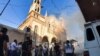 People gather at the scene of a car bomb explosion outside the Syriac Orthodox Church of the Virgin Mary in the predominantly Christian neighborhood of al-Wasti in the Kurdish-majority city of Qamishli in northeast Syria, July 11, 2019. 