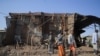 FILE - Residents and militia members stand next to houses destroyed by an airstrike during the fight between the Ethiopian National Defense Forces and the Tigray People's Liberation Front in Kasagita, Afar region, Ethiopia, Feb. 25, 2022.
