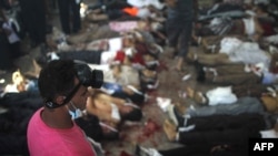 FILE - A man looks at bodies laid out in a make shift morgue after Egyptian armjy and police forces stormed two huge protest camps at the Rabaa al-Adawiya and Al-Nahda squares, killing hundreds of supporters of ousted president Mohamed Morsi, Cairo, August 14, 2013.