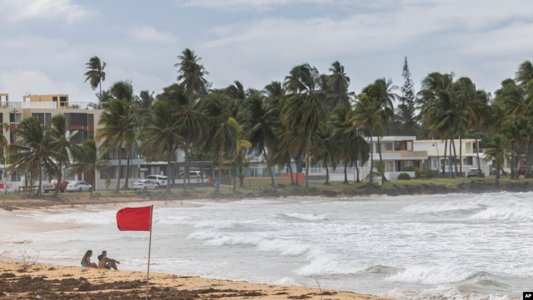 Turistas captados en playa La Pared mientras la tormenta tropical Ernesto pasa por Luquillo, Puerto Rico, el martes 13 de agosto de 2024.