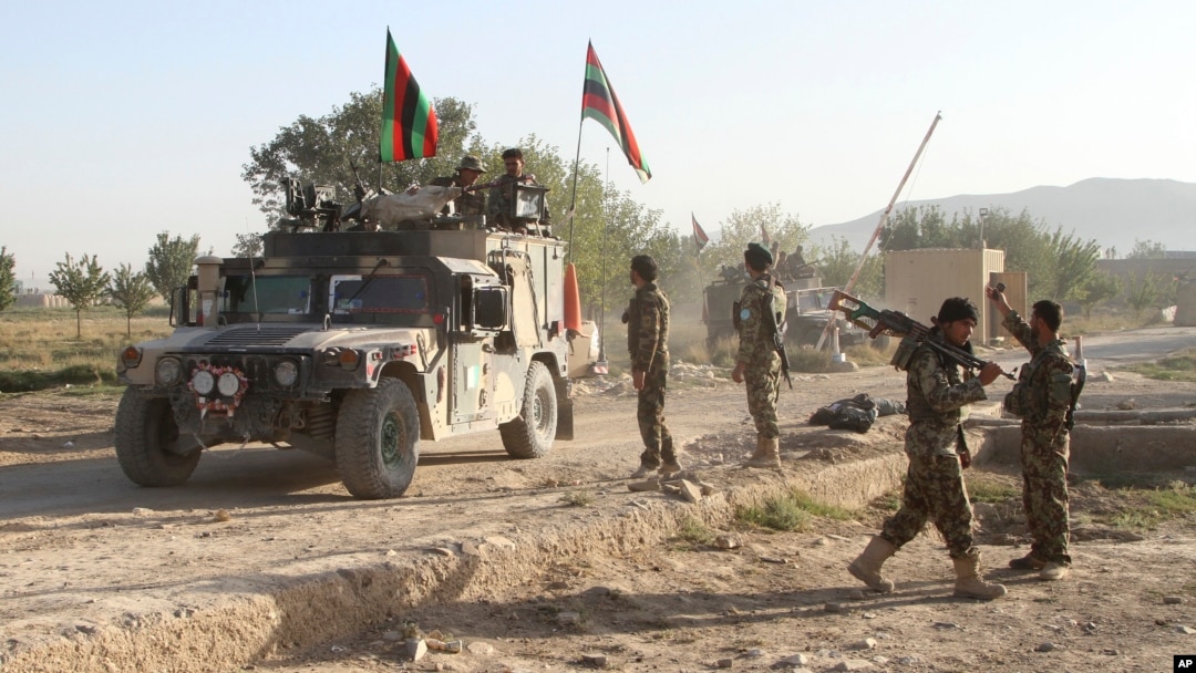 Afghan national army stand guard near the dead body of a Taliban attacker in front of the main prison building after an attack in Ghazni province, eastern Afghanistan, Monday, Sept. 14, 2015.