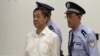 In this image taken from video, disgraced politician Bo Xilai, center, enters the courtroom, flanked by police guards at Jinan Intermediate People's Court in eastern China's Shandong province, Aug. 22, 2013. 