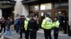 Police officers and security watch as people re-enter a building after a stabbing incident in central London, Friday, Nov. 2, 2018. 