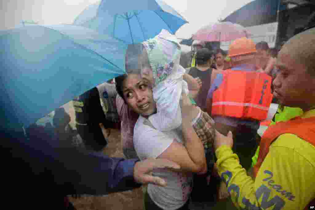 A woman carries his baby as they are evacuated by rescuers in Marikina, east of Manila, Philippines, August 7, 2012.