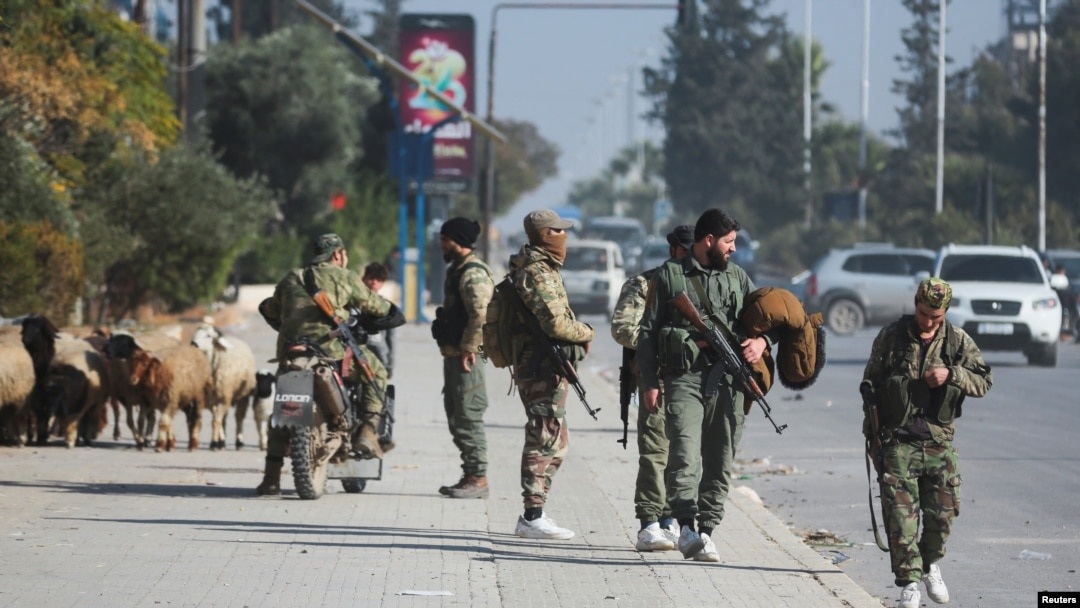 Opposition fighters walk along a street in Aleppo, Syria, after the government army said dozens of its soldiers were killed in a major attack by rebels who swept into the city on Nov. 30, 2024.