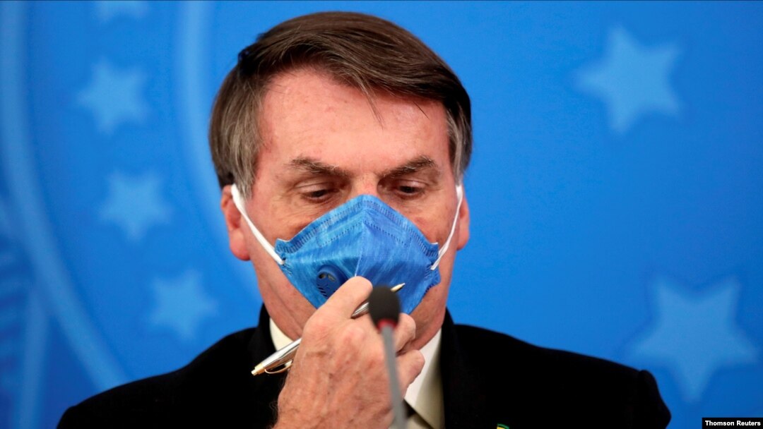 FILE PHOTO: Brazil's President Jair Bolsonaro adjusts his protective face mask at a press statement during the coronavirus disease (COVID-19) outbreak in Brasilia
