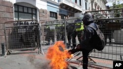 Un manifestante patea una llanta en llamas en una barricada policial que impedía el acceso al Palacio Presidencial en Quito, Ecuador, el 25 de mayo de 2020.