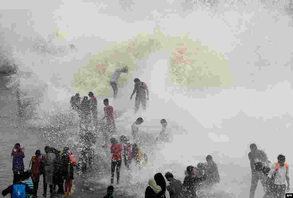 在印度孟买，涨潮时分，人们在海边迎接海浪（6月28日）