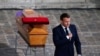 French President Emmanuel Macron leaves after paying his respects by the coffin of slain teacher Samuel Paty in the courtyard of the Sorbonne university during a national memorial event, Oct. 21, 2020, in Paris. 
