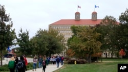FILE - Students walk in front of Fraser Hall on the University of Kansas campus in Lawrence, Kan. Students cite the cost of flights, and worries about visa renewal as the main reasons for not traveling. 