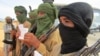 FILE - Young fighters display their Quranic studies notes for a journalist as their Islamist commanders look on, in Douentza, Mali.