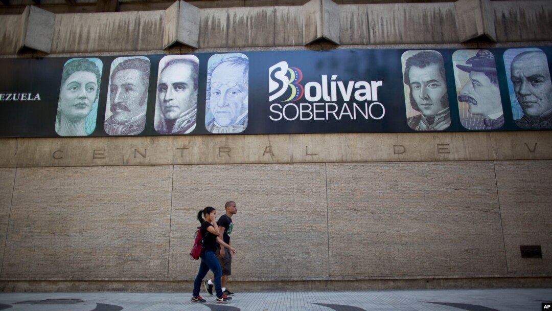 Peatones pasan junto al Banco Central de Venezuela, que despliega carteles con la moneda local, en el centro de Caracas.