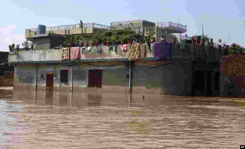 Residents wait on the top floor of their deluged house following heavy monsoon rains in Wazirabad, some 100 kilometers (65 miles) north of Lahore, Pakistan, Sept. 7, 2014.