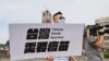 A lawmaker from Taiwan's main opposition Kuomintang (KMT) Party holds signs calling for the government to accept all vaccines and provide free vaccines for all citizens, in front of the Presidental building in Taipei, Taiwan, June 4, 2021. 