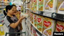 A sales assistant (back) helps a customer to select Dumex milk powder at a supermarket in Hefei, Anhui province, August 5, 2013.