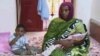 FILE - Meriam Ibrahim, sitting next to Martin, her 18-month-old son, holds the newborn daughter she gave birth to in jail in May at a prison in Khartoum, Sudan. 