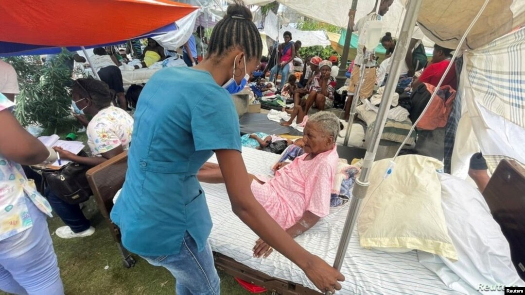 Una mujer es atendida por un miembro del personal médico afuera de un hospital después del terremoto de magnitud 7,2 del sábado, en Les Cayes, Haití, el 16 de agosto de 2021.