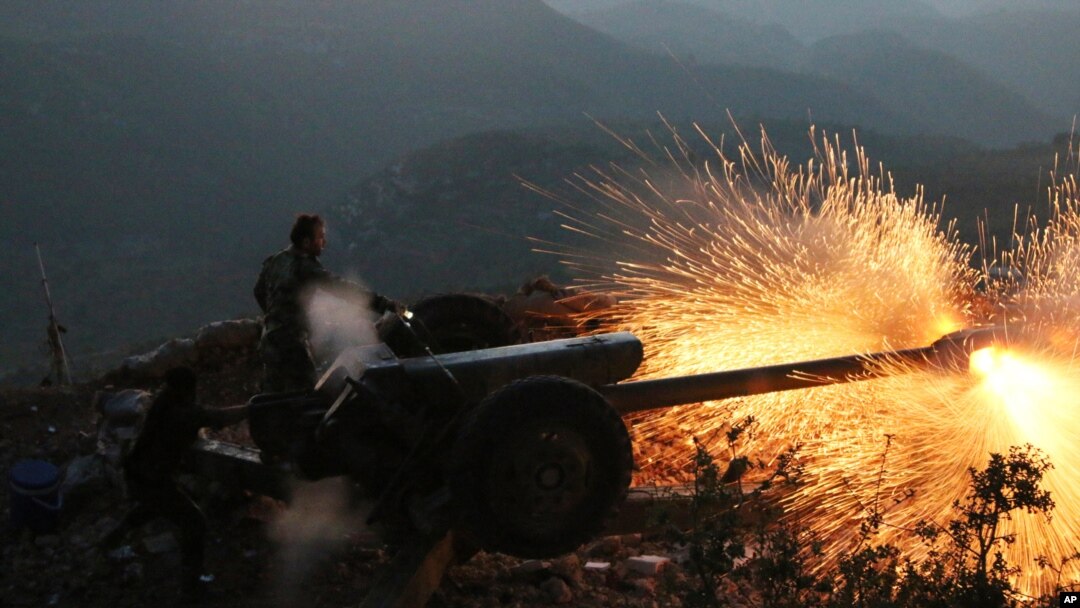 Syrian army personnel backed by Russian airstrikes fire cannon in Latakia province, near the border with Turkey, Oct. 10, 2015.