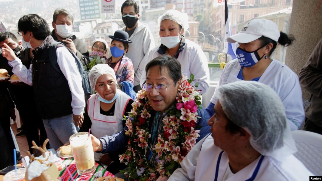 Luis Arce, el candidato del Movimiento al Socialismo (MAS), quien lidera las encuestas, comparte con trabajadores de un mercado de verduras en La Paz, Bolivia, el 10 de octubre de 2020.